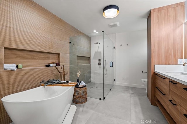 full bath featuring tile walls, toilet, a shower stall, vanity, and a freestanding tub