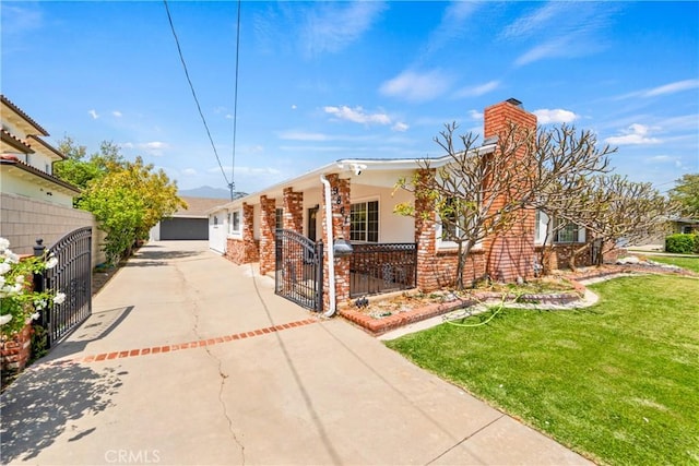 view of front facade with brick siding, fence, driveway, a front lawn, and a chimney