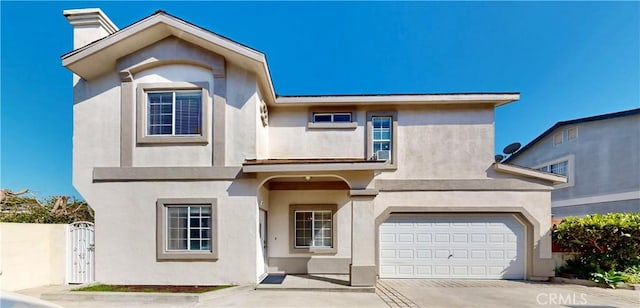 traditional-style home with driveway, a chimney, an attached garage, a gate, and stucco siding