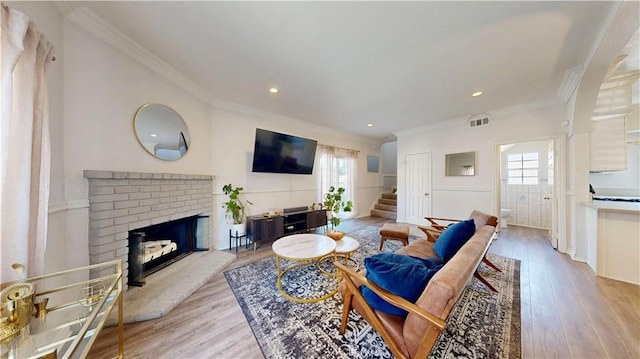 living area featuring wood finished floors, visible vents, a fireplace, and stairs