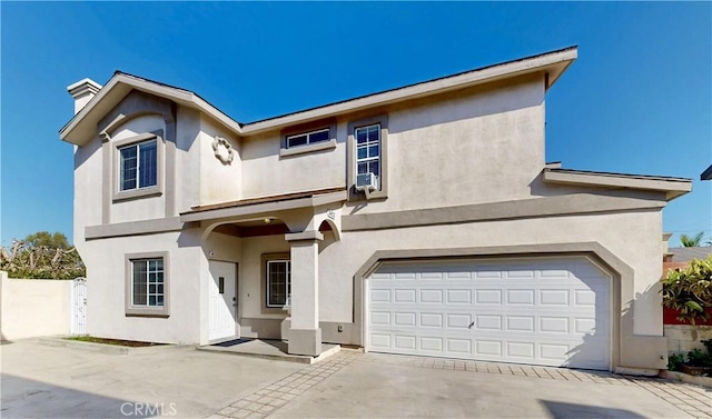 traditional-style home with a garage, fence, concrete driveway, and stucco siding