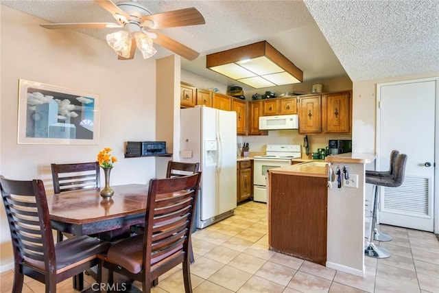 kitchen featuring a peninsula, white appliances, light countertops, and light tile patterned flooring