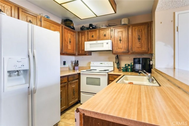 kitchen featuring light tile patterned floors, white appliances, a sink, wood counters, and brown cabinetry