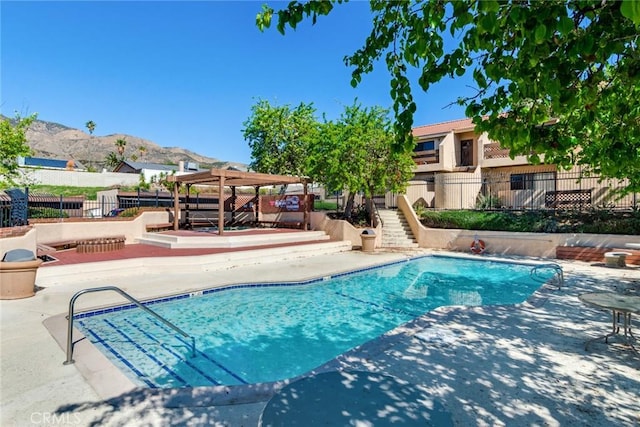 pool with fence, a mountain view, a pergola, and a patio