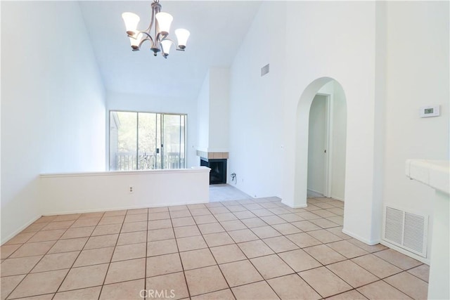 empty room with high vaulted ceiling, arched walkways, a chandelier, and visible vents