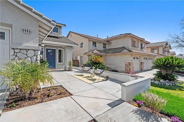 view of front of home featuring a garage, concrete driveway, a tile roof, and stucco siding