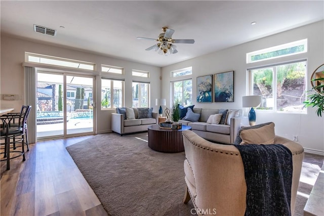 living area featuring a ceiling fan, visible vents, and wood finished floors