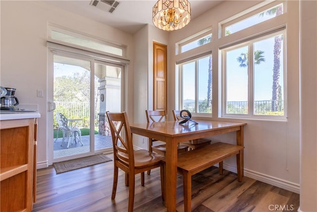 dining room with baseboards, light wood finished floors, visible vents, and a notable chandelier