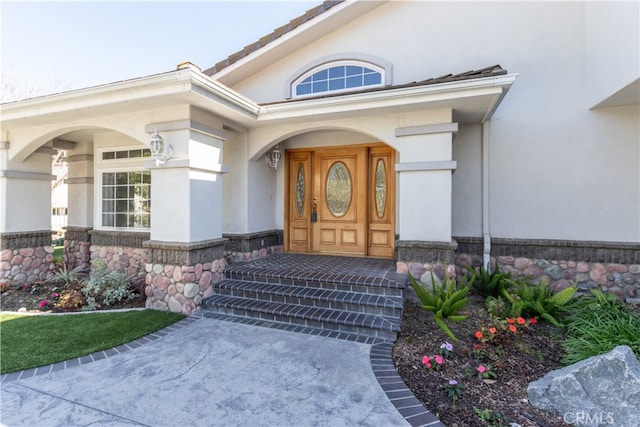 doorway to property with stone siding and stucco siding