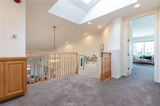 hall with carpet, vaulted ceiling with skylight, an upstairs landing, and recessed lighting