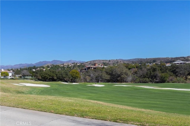 view of property's community featuring view of golf course, a lawn, and a mountain view