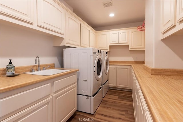 laundry area featuring dark wood-style floors, visible vents, cabinet space, washing machine and dryer, and a sink