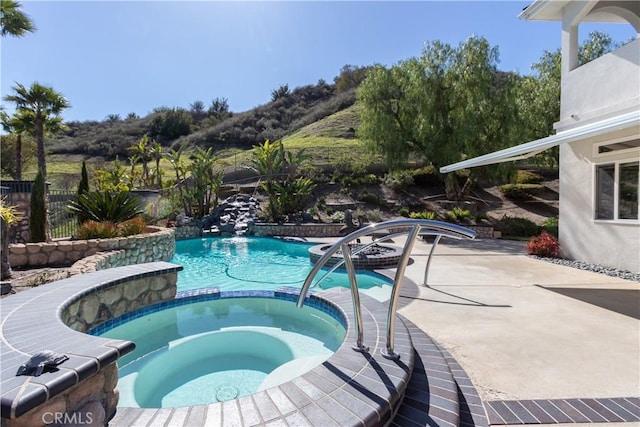 view of swimming pool with a pool with connected hot tub, a patio area, and fence