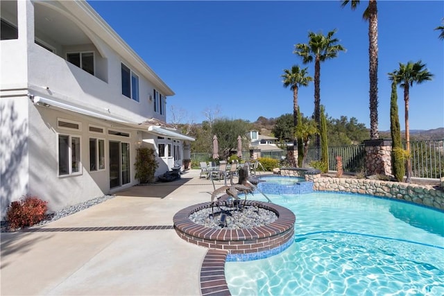 view of swimming pool featuring a pool with connected hot tub, fence, and a patio