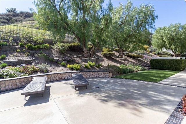 view of community with a patio, a yard, and fence