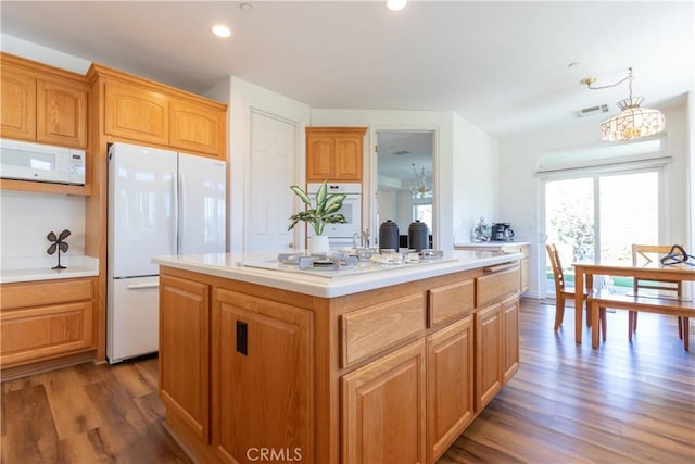 kitchen with dark wood-type flooring, a center island, white appliances, and light countertops