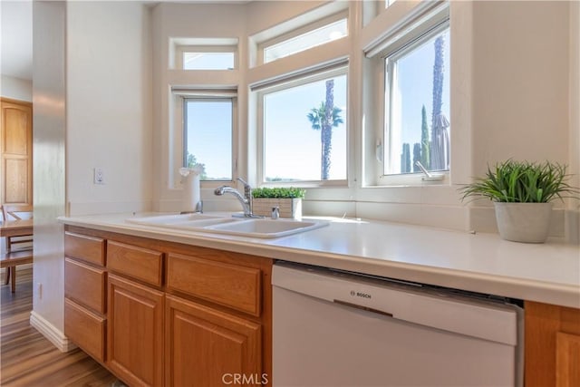 kitchen featuring light countertops, dishwasher, light wood-style flooring, and a sink