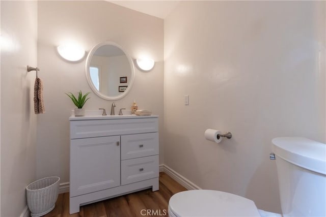 bathroom featuring vanity, wood finished floors, toilet, and baseboards