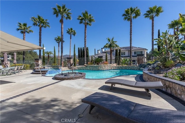 community pool with a hot tub, fence, and a patio