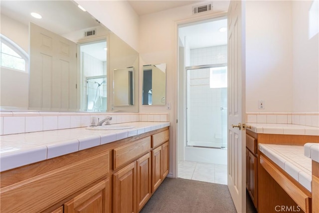 bathroom with combined bath / shower with glass door, tile patterned flooring, vanity, and visible vents