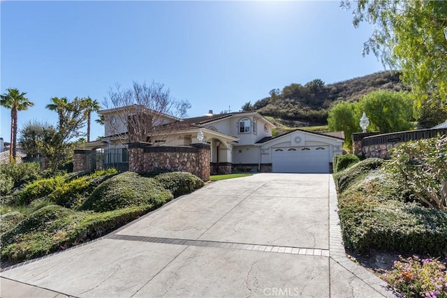 view of front facade featuring driveway, an attached garage, and fence