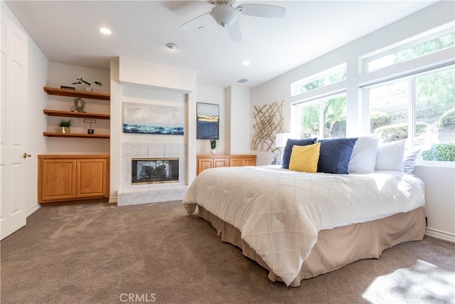 bedroom with a tiled fireplace, carpet, a ceiling fan, and recessed lighting