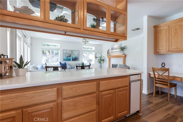 kitchen featuring dark wood-type flooring, visible vents, open floor plan, light countertops, and glass insert cabinets