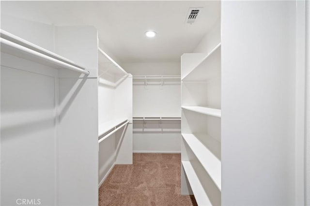 walk in closet with light colored carpet and visible vents