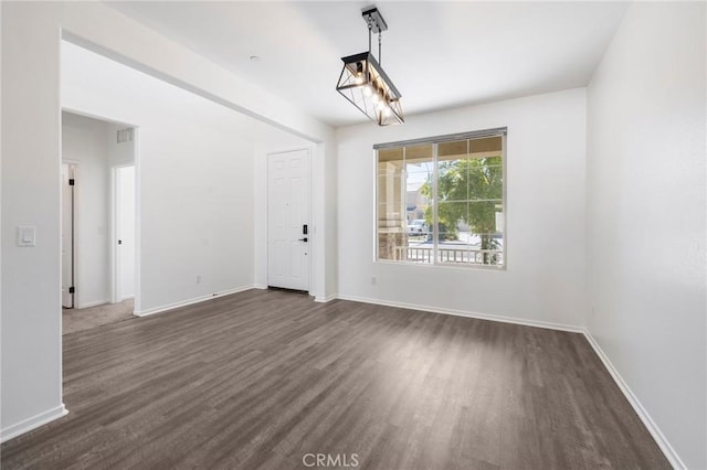 spare room featuring dark wood-type flooring, visible vents, and baseboards