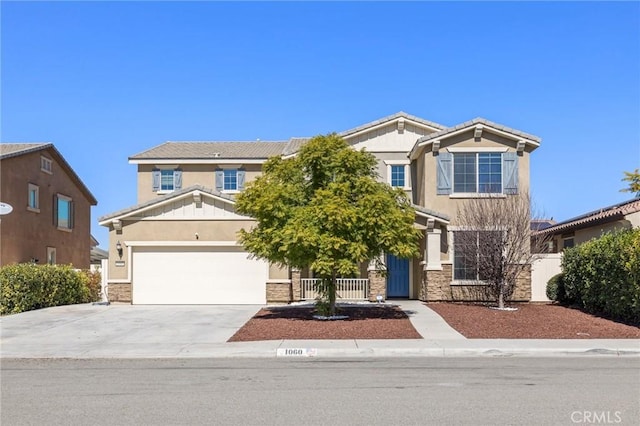 craftsman inspired home featuring a garage, concrete driveway, stone siding, fence, and stucco siding