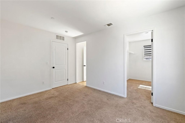 unfurnished bedroom featuring baseboards, a spacious closet, visible vents, and carpet flooring