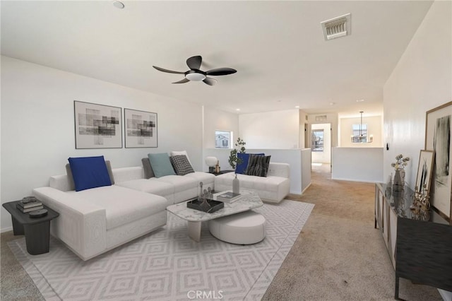 living area with light colored carpet, visible vents, ceiling fan, and baseboards