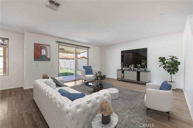 living area with baseboards, visible vents, and wood finished floors