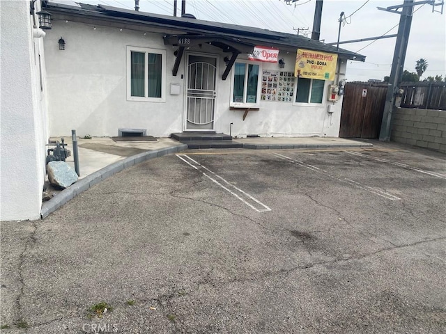 exterior space with uncovered parking, fence, and stucco siding