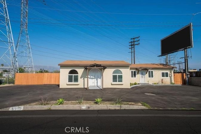 view of front of house featuring fence, aphalt driveway, and stucco siding