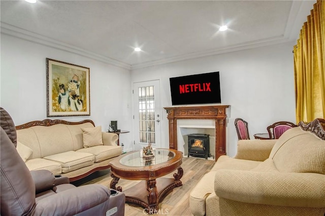 living room with recessed lighting, wood finished floors, a wood stove, and crown molding