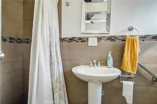 bathroom featuring a tile shower, a ceiling fan, and tile walls