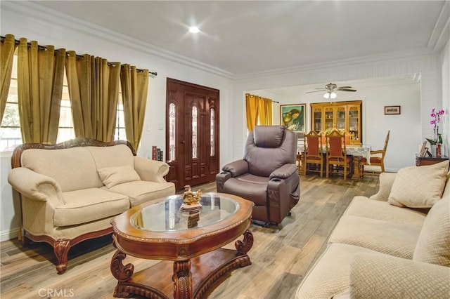 living room with light wood-style floors, ceiling fan, and crown molding