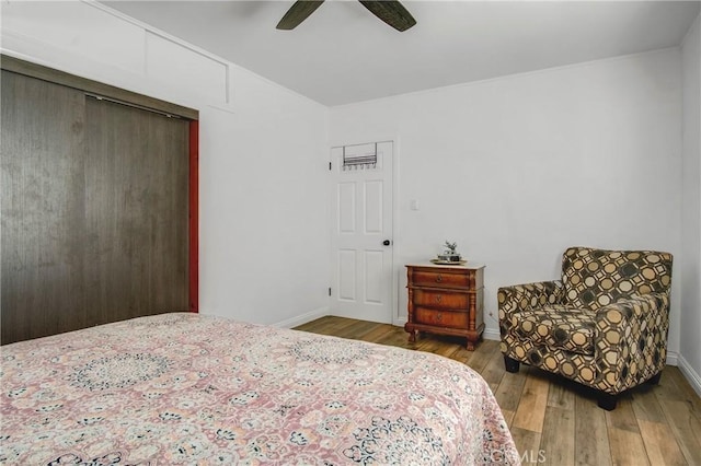 bedroom with hardwood / wood-style floors, a closet, a ceiling fan, and baseboards