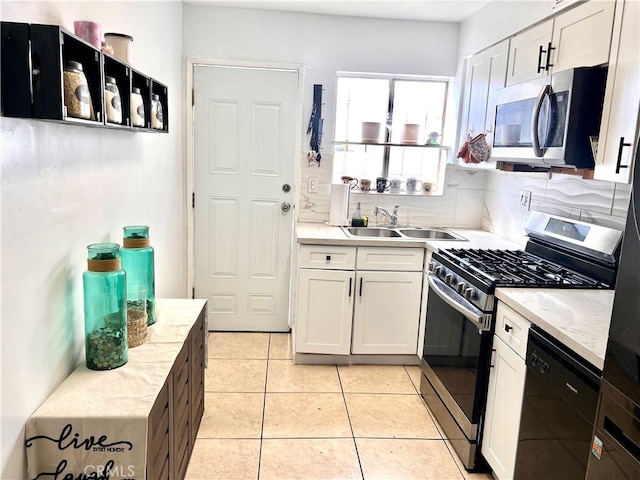 kitchen with tasteful backsplash, appliances with stainless steel finishes, light tile patterned flooring, white cabinets, and a sink