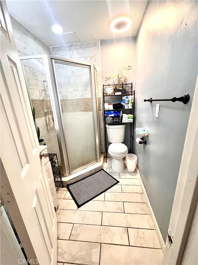 full bath featuring baseboards, toilet, and a shower stall