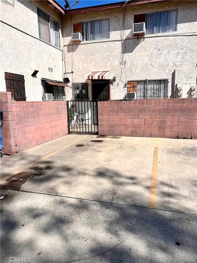 view of gate featuring fence and a wall mounted air conditioner