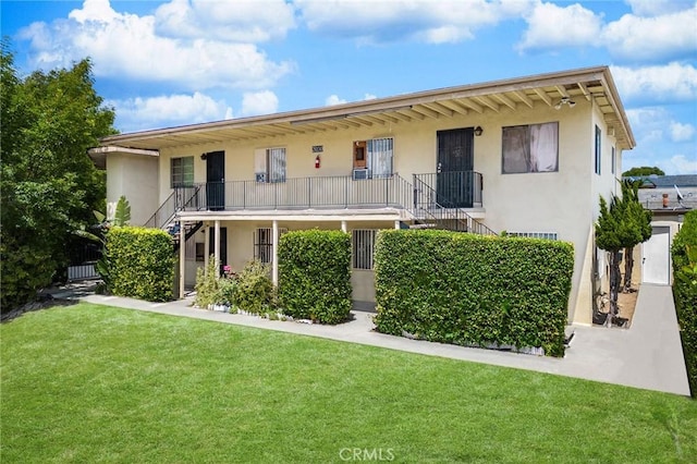 view of front of home featuring stairs, a front yard, and stucco siding