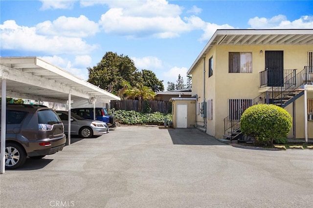 covered parking lot featuring fence and stairway