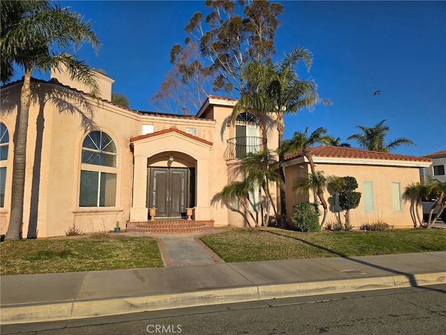 mediterranean / spanish home with a front yard and stucco siding