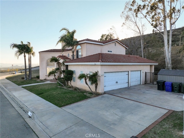 view of front facade featuring driveway, stucco siding, an attached garage, fence, and a front yard