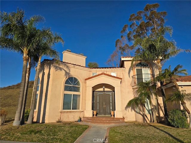 view of front of house featuring a front lawn, a chimney, and stucco siding