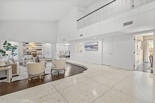 living room featuring visible vents, a towering ceiling, and baseboards