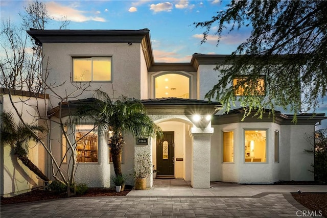 back of property at dusk with stucco siding