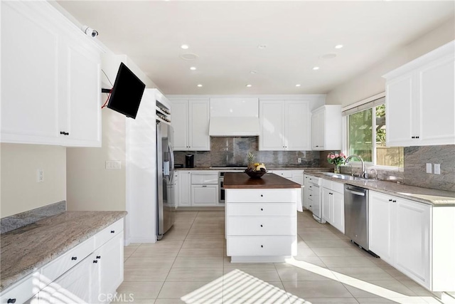 17846 Palora St, Encino, CA 91316 - kitchen with custom exhaust hood, stainless steel appliances, a sink, white cabinetry, and backsplash